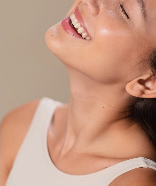 Smiling woman with glowing skin and head tilted back in joy Smiling woman with glowing skin and head tilted back in joy